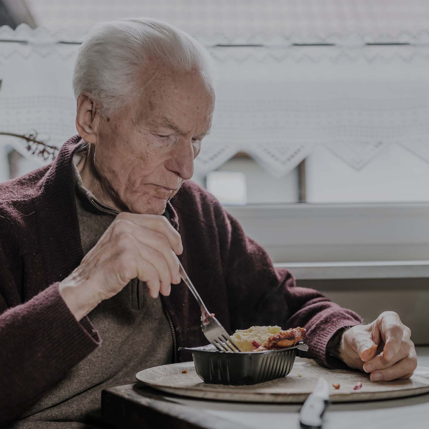 Elderly man enjoying a meal indoors.