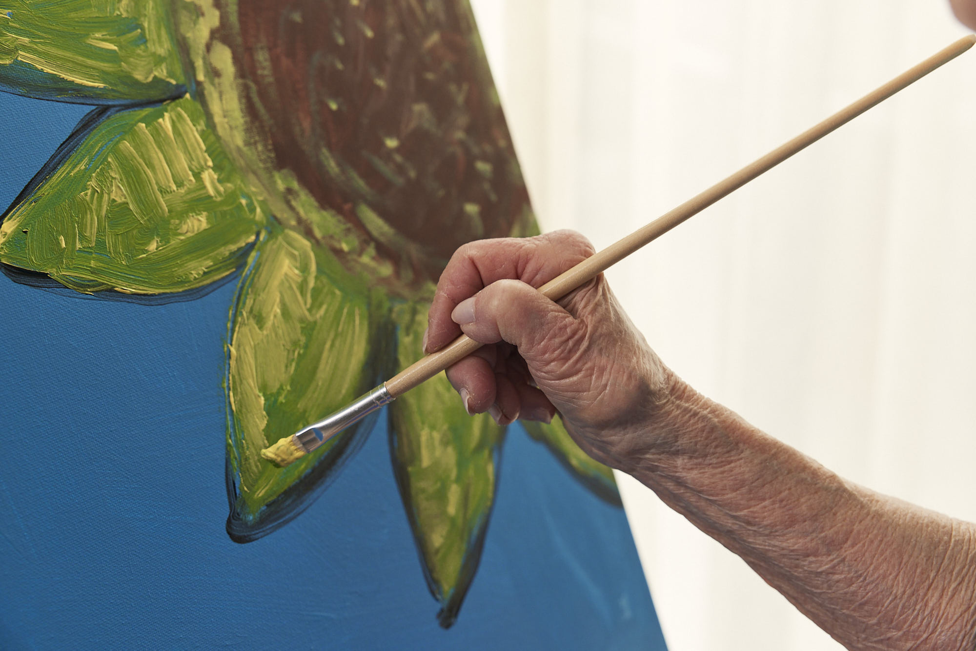 A hand painting a sunflower.