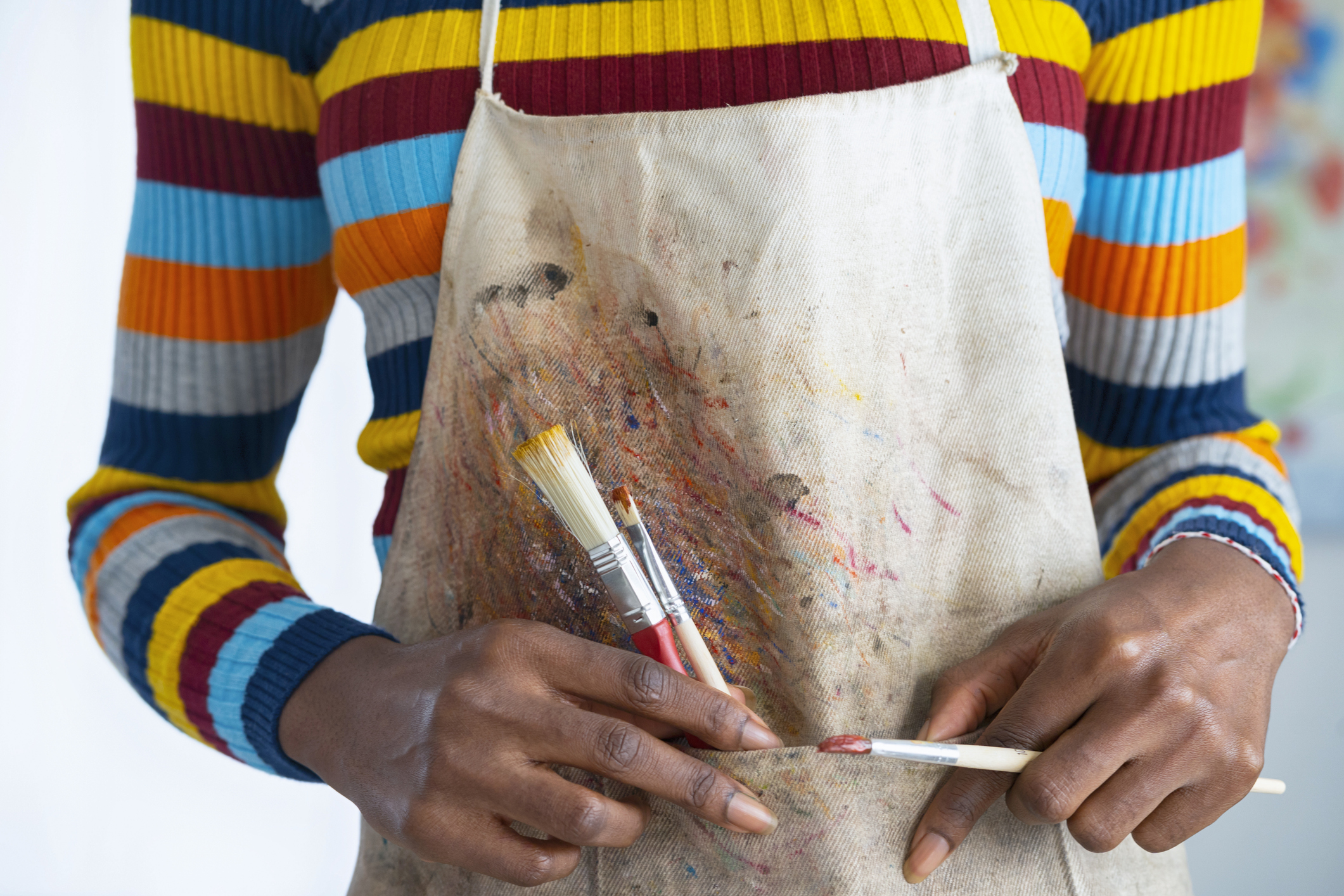 Person holding paintbrushes in an apron