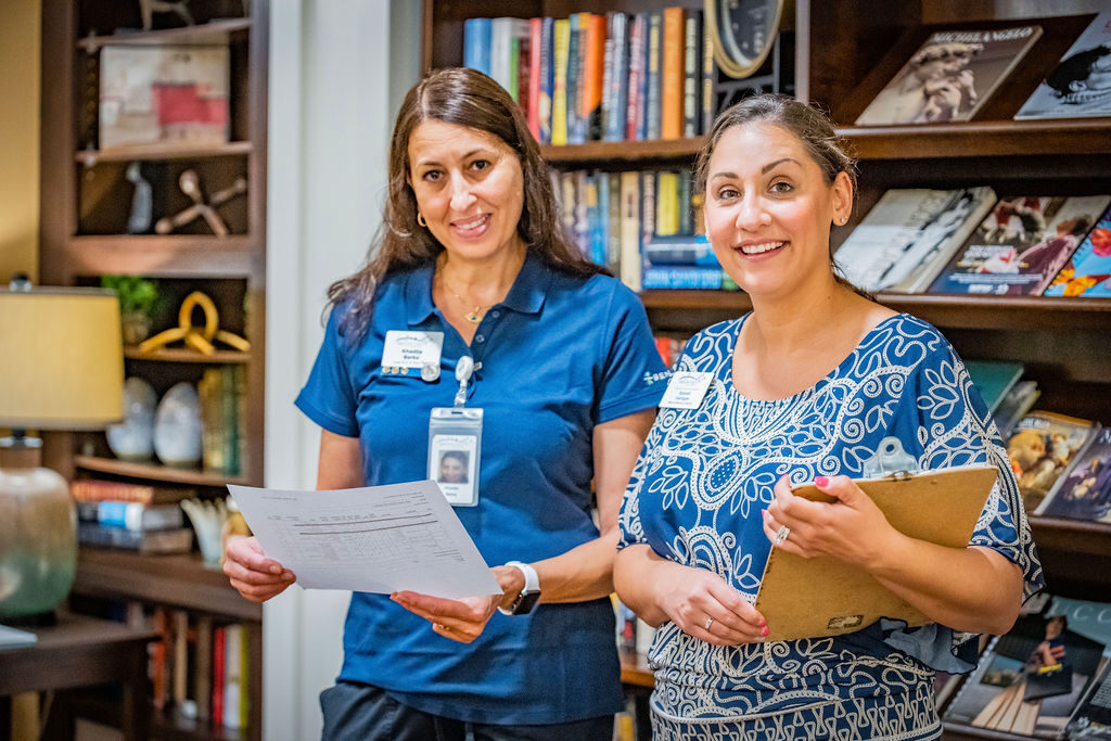 Two staff members smiling in a library area.