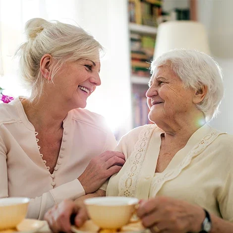 Two women enjoying tea and conversation in a cozy setting.