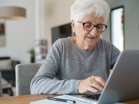 Senior woman using a laptop in an indoor setting.
