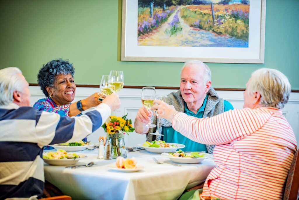 Residents enjoying a meal and toasting at a dining table.