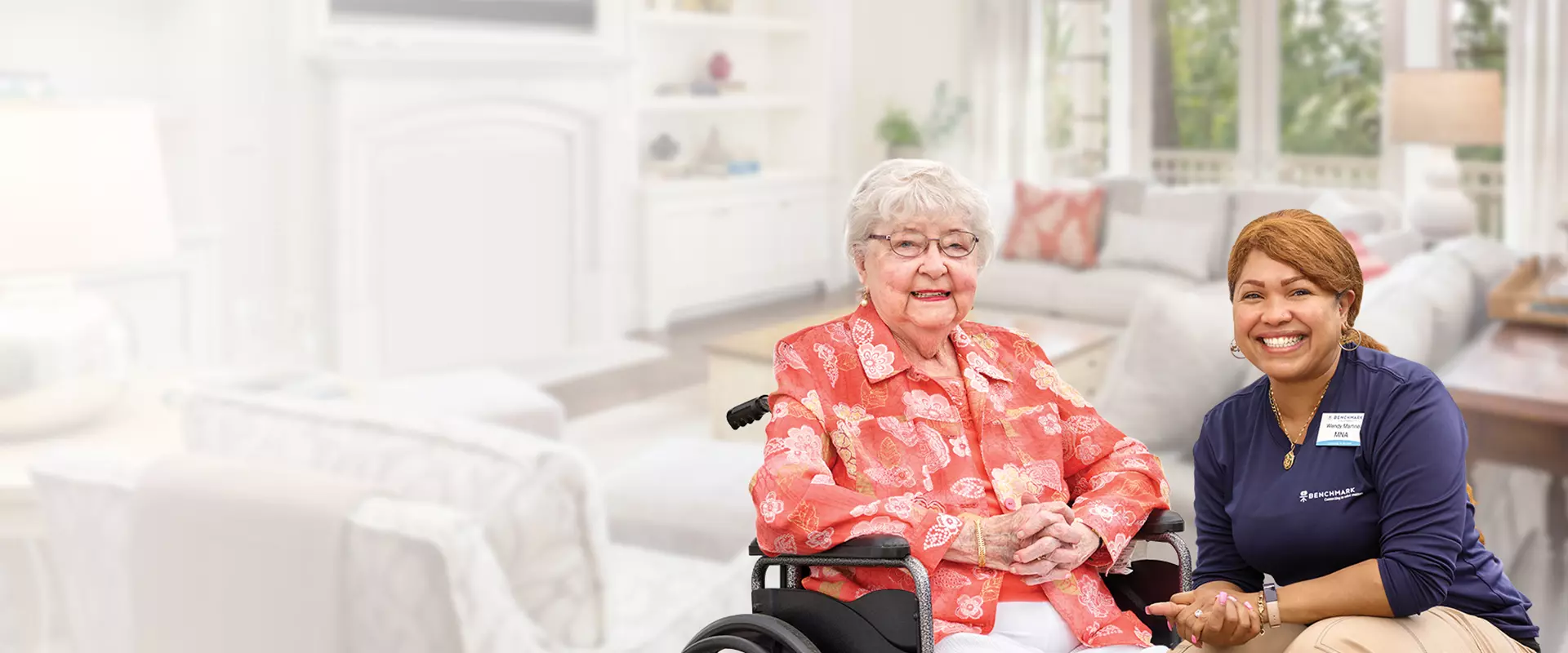 Resident and staff member smiling in a cozy living area.
