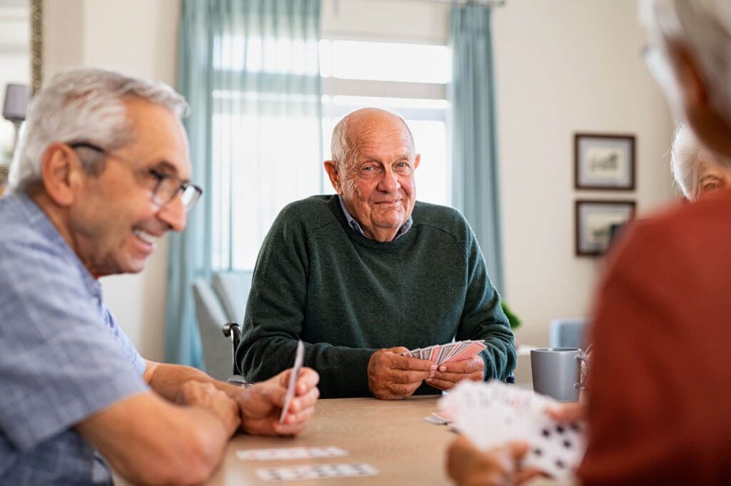 Seniors playing cards together in a bright room
