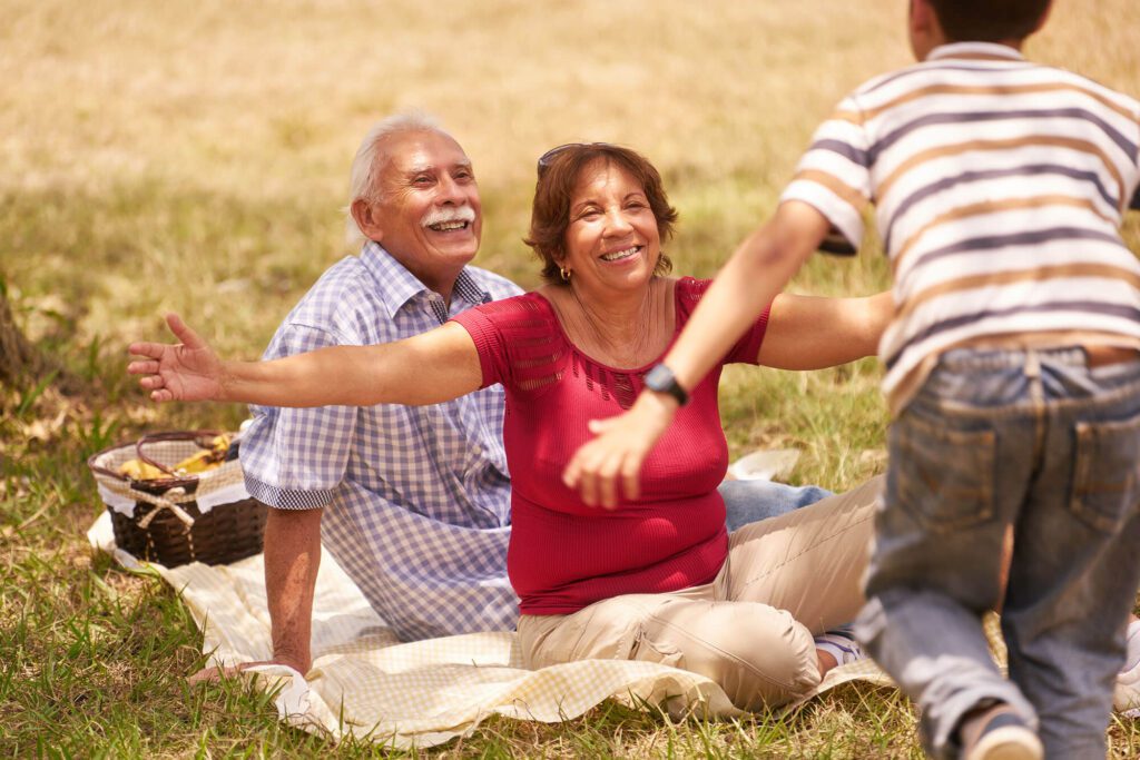 Seniors enjoying a picnic with a child in a park.