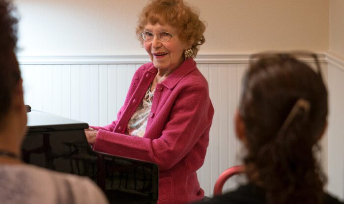 Elderly woman playing piano during a group activity