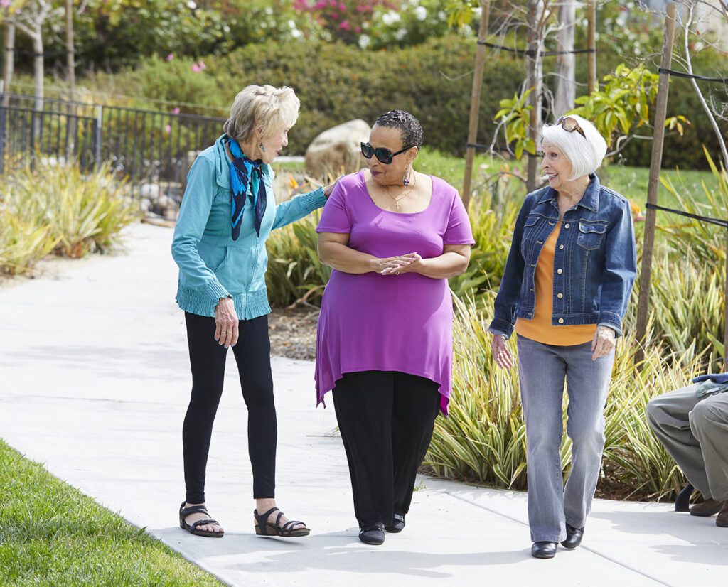 Three residents enjoying a walk in the garden.