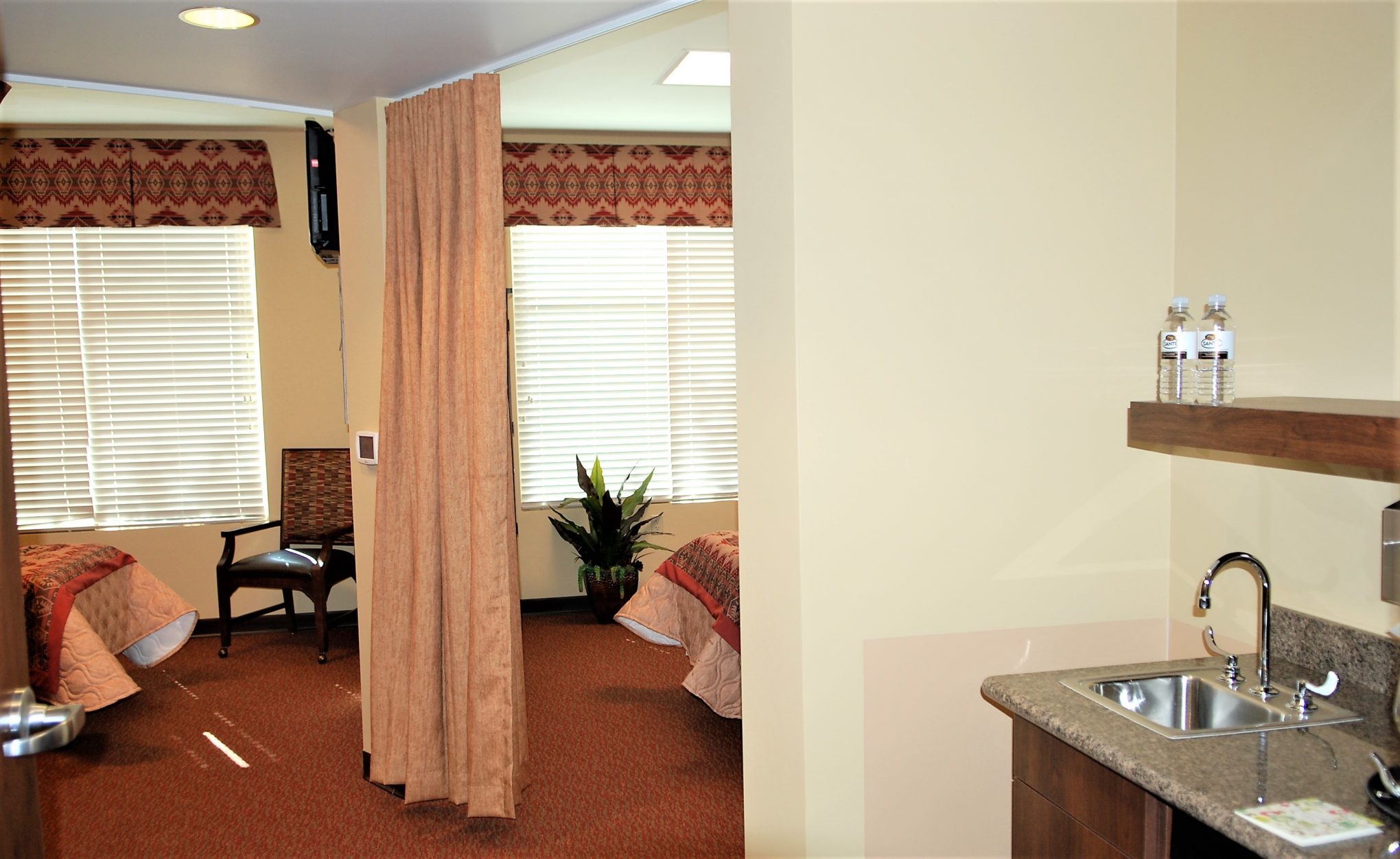 Bright shared living space with two beds and kitchenette.