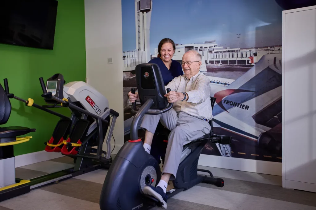 Elderly man exercising with staff assistance