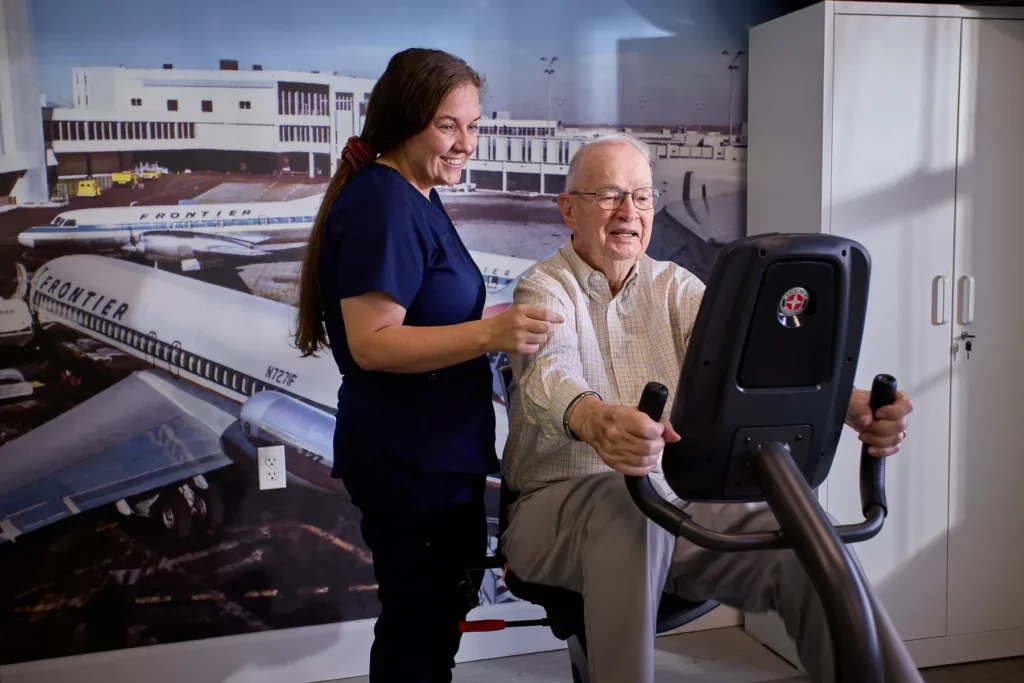 Staff assisting a resident on exercise equipment