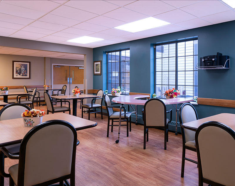 Bright dining area with tables and flowers.