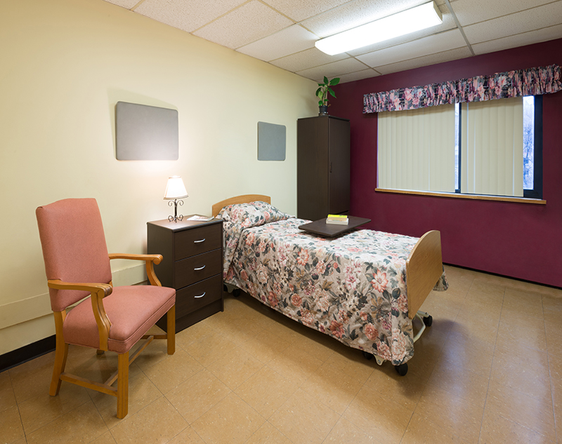 Cozy resident room with bed and chair.