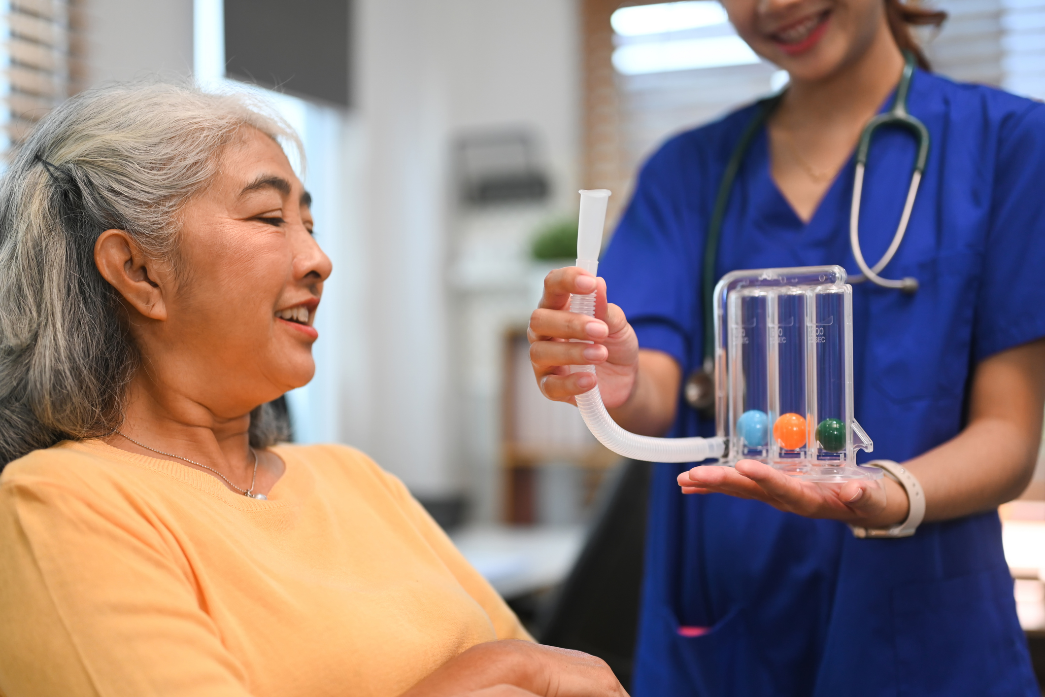 Healthcare worker assisting an elderly woman with a therapy tool.