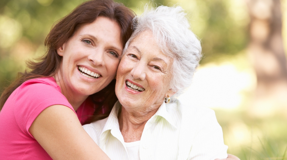 Happy woman and elderly resident embracing outdoors.