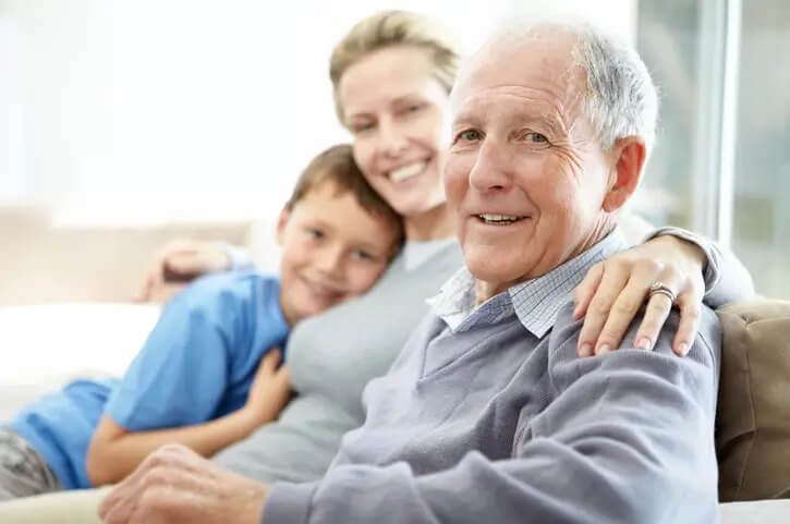 Smiling elderly man with family on couch