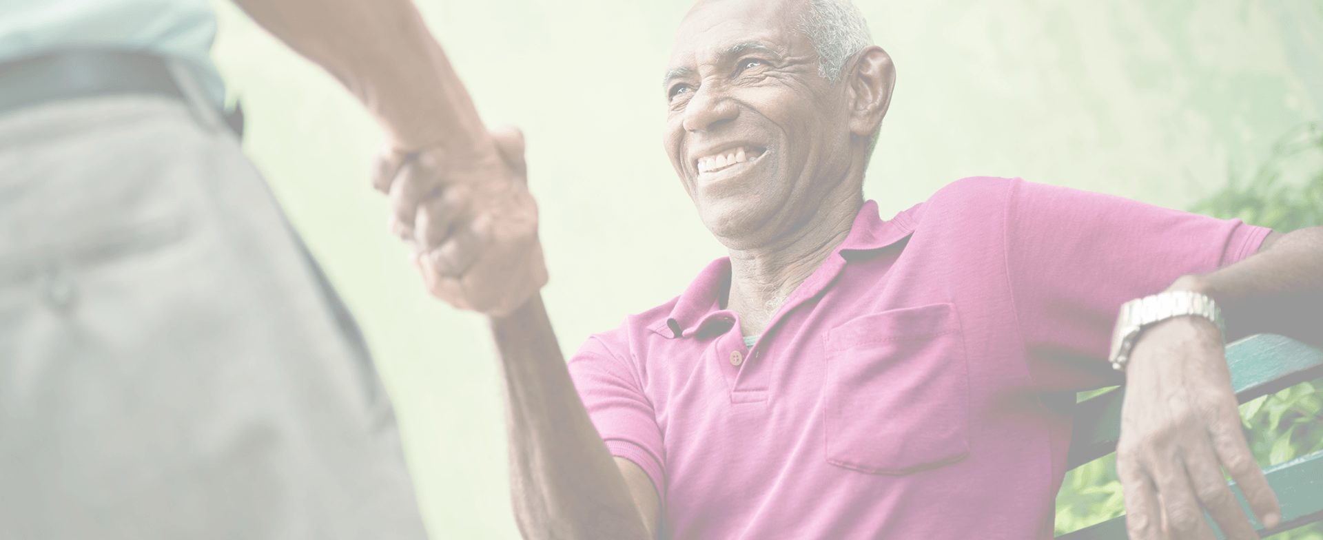 An elderly man smiling while shaking hands.