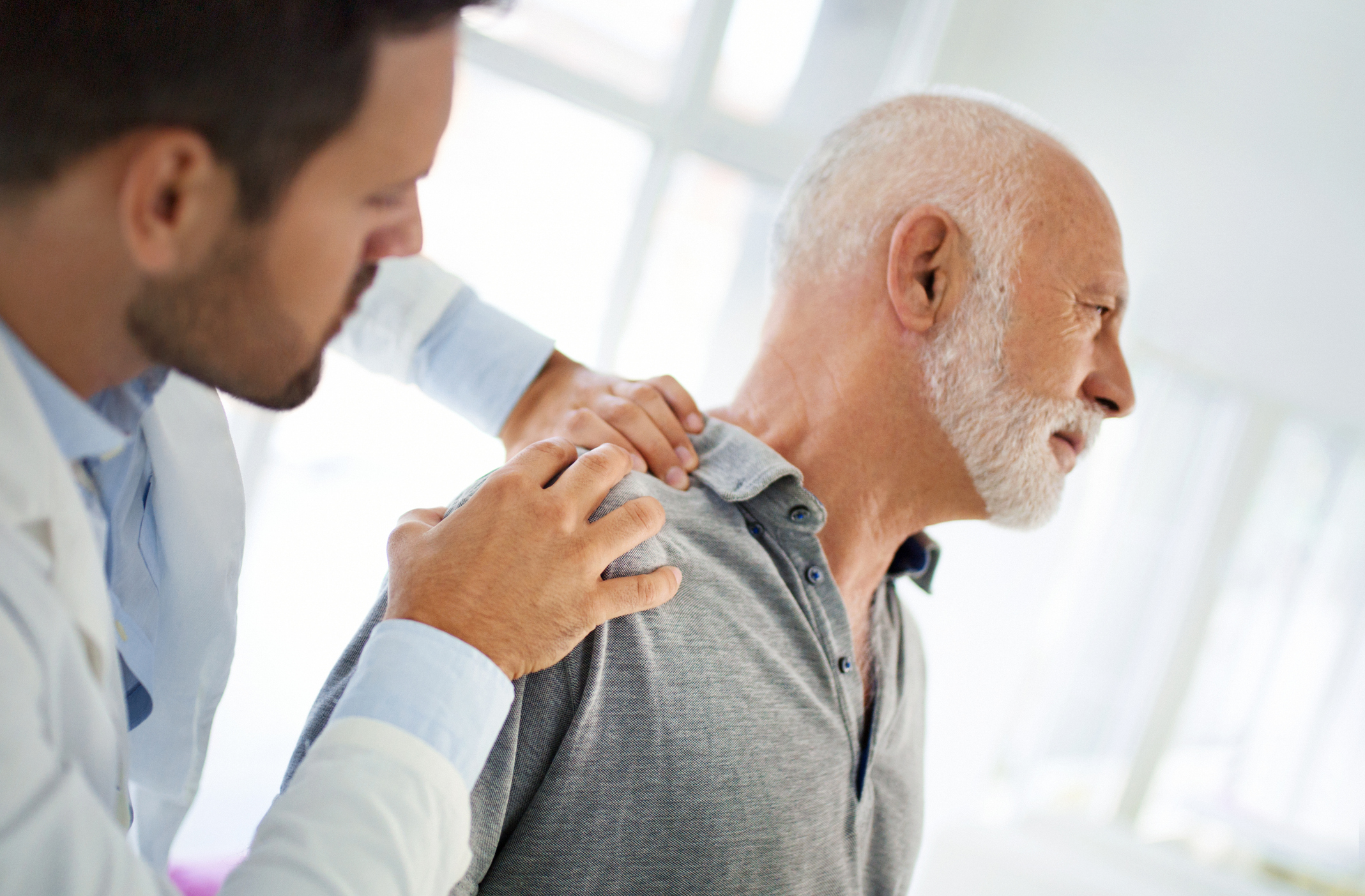 Caregiver assisting an elderly man with therapy