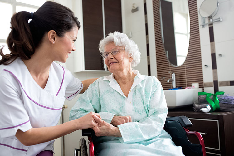 Caregiver interacting with elderly resident in a room.