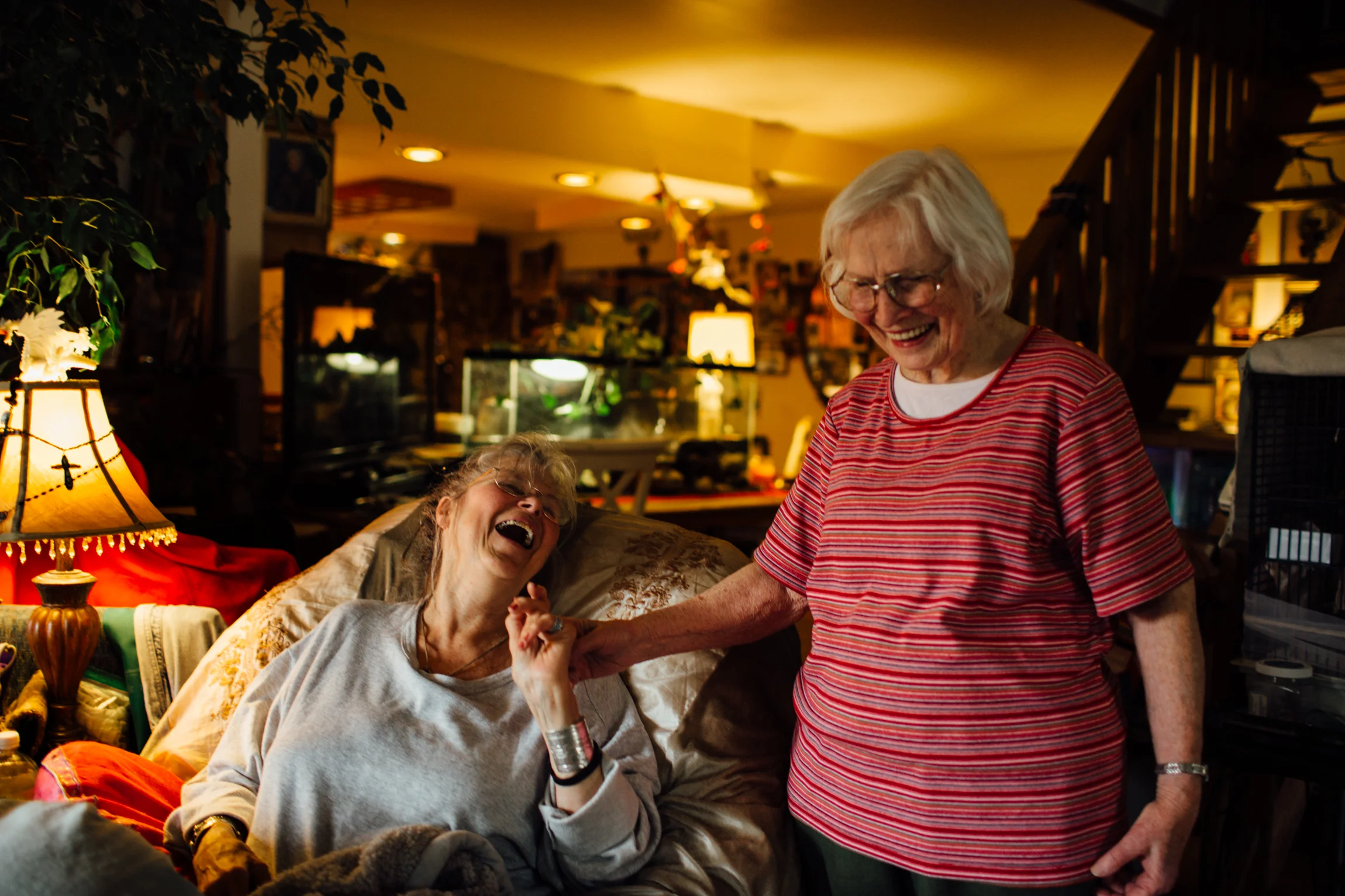 Two smiling women sharing a joyful moment indoors.
