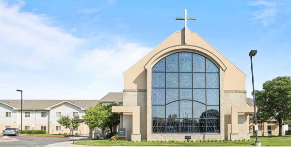 Exterior view of a facility with a cross and large windows.