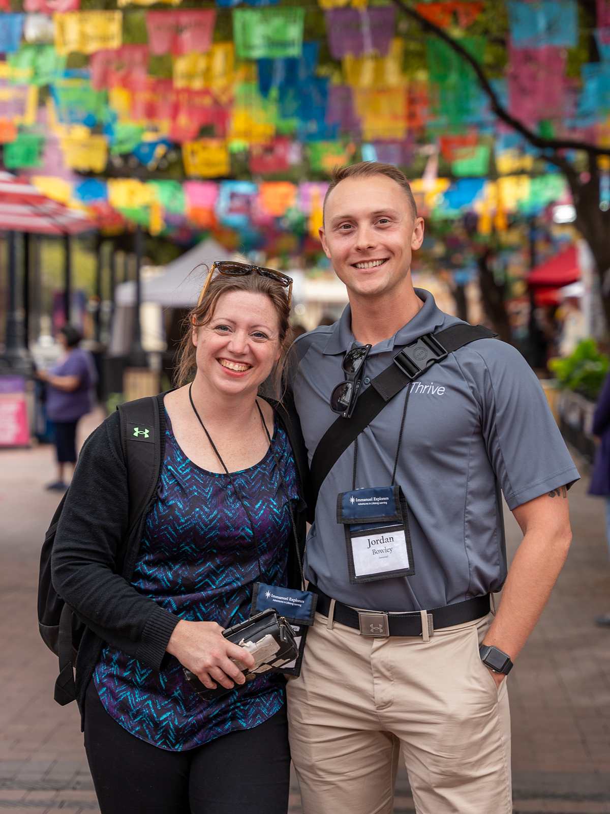 Two people smiling in a colorful outdoor setting.