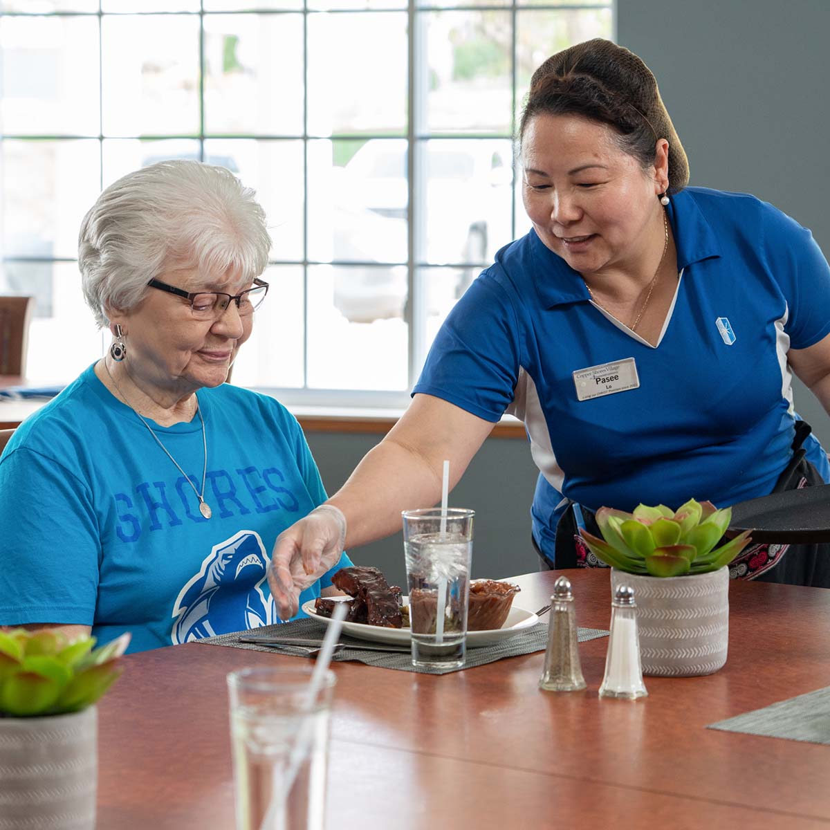 Staff serving dessert to a resident in dining area.