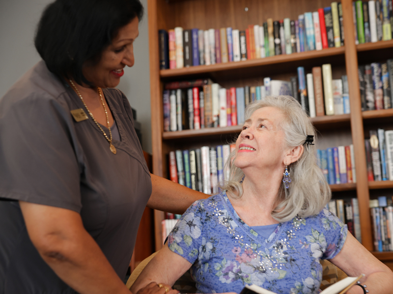 Staff member interacting with a resident in a library setting.