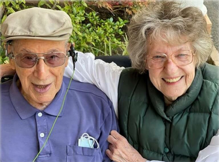 Smiling elderly couple posing together outdoors.