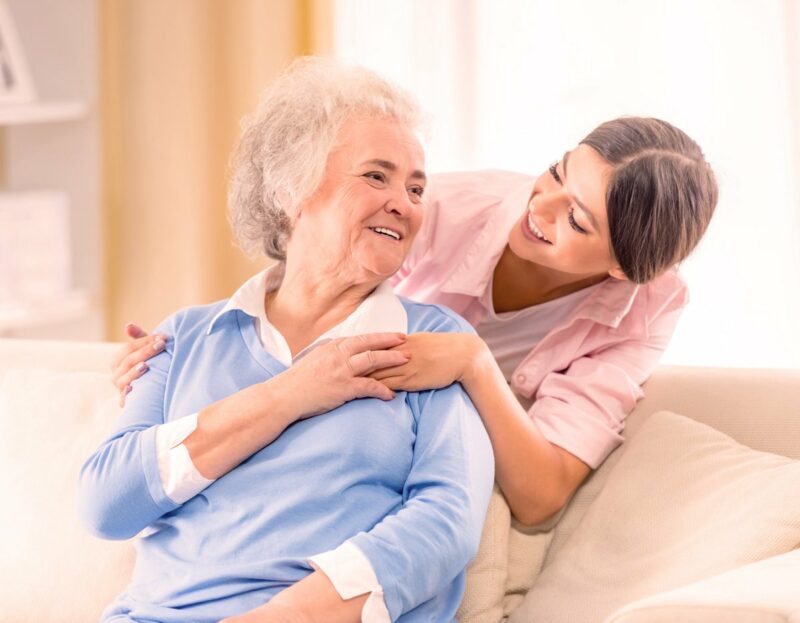 A caregiver smiling with a resident in a cozy room.
