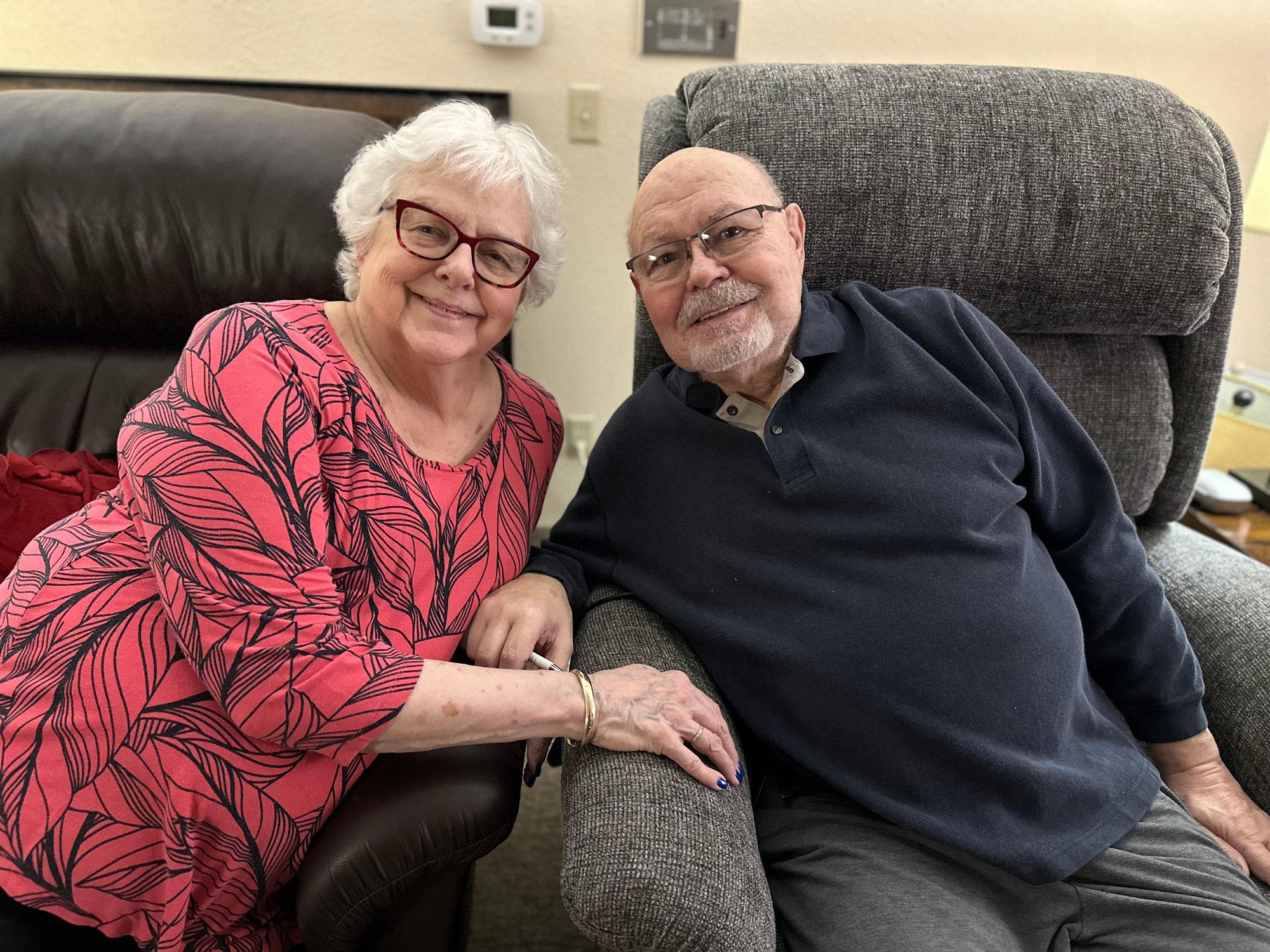 Two smiling residents posing in comfortable chairs.