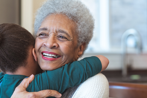Elderly woman hugging a child in a warm setting.