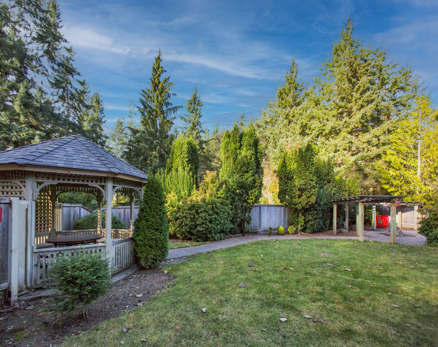 Outdoor garden with gazebo and trees.