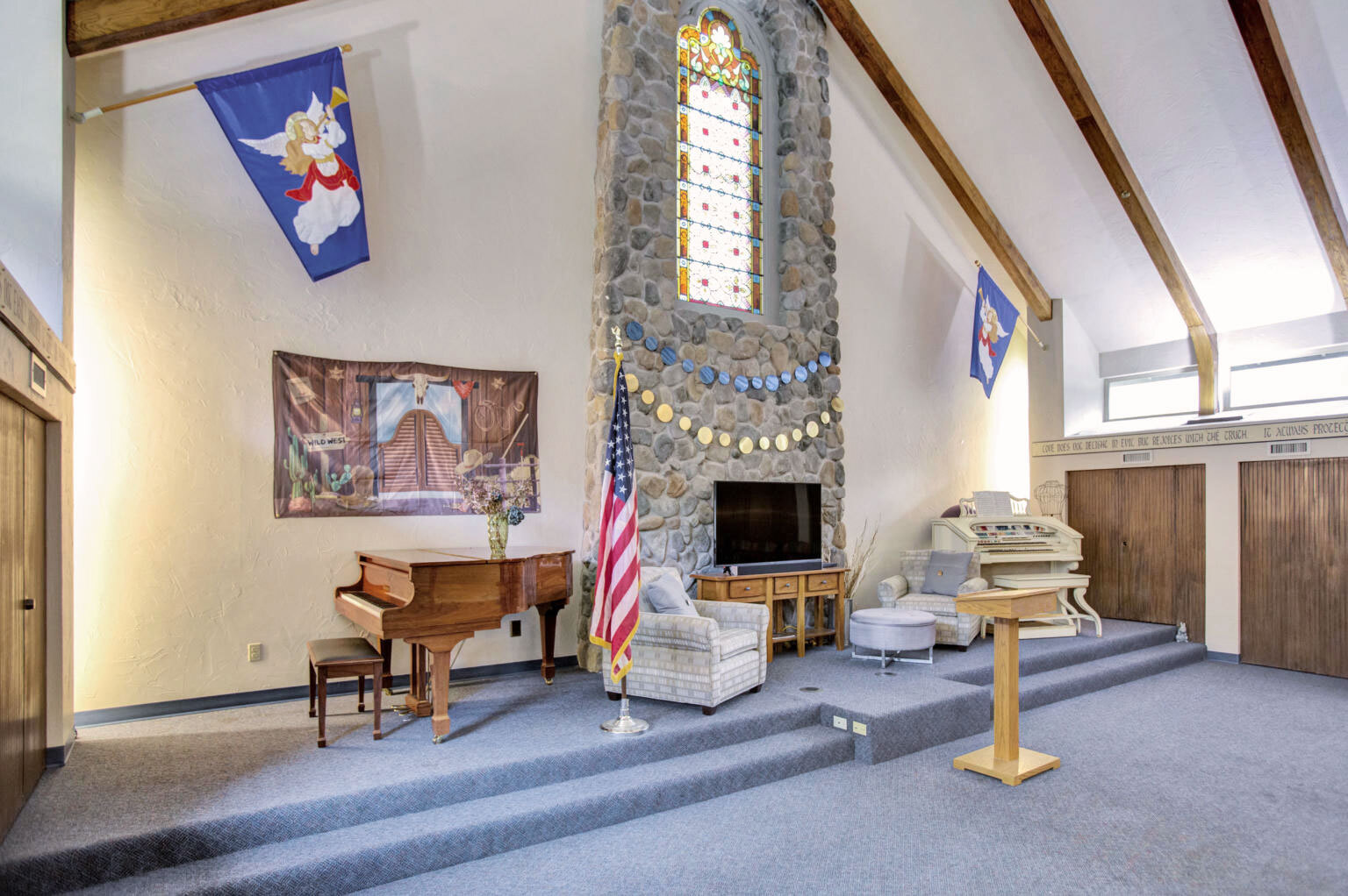 Interior view of a communal space with a stage and piano.