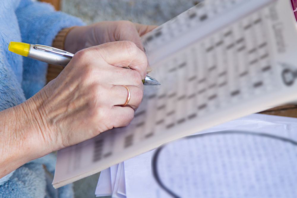 Close-up of a hand writing on a puzzle.