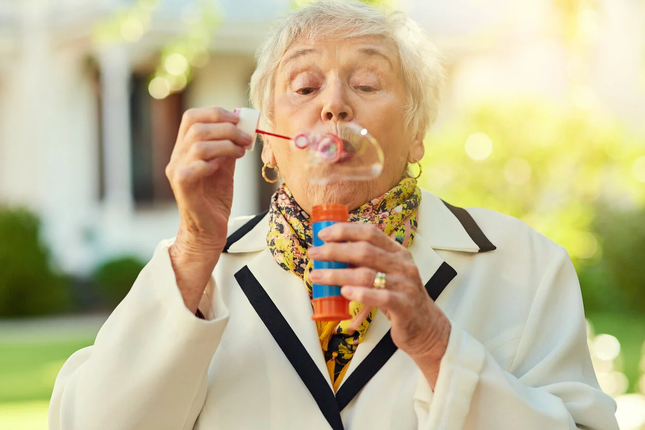 Elderly woman blowing bubbles outdoors