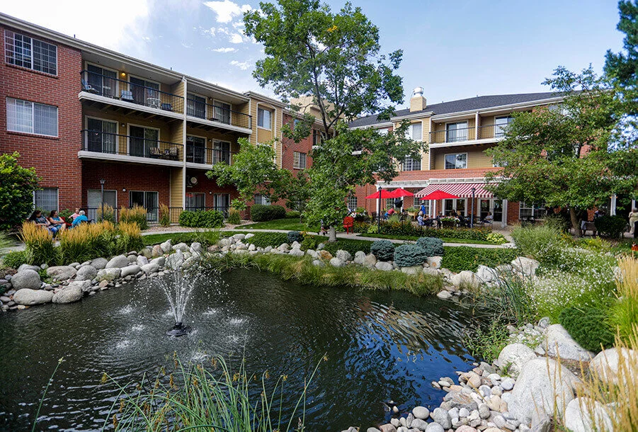 Lush outdoor area with a pond and residents relaxing