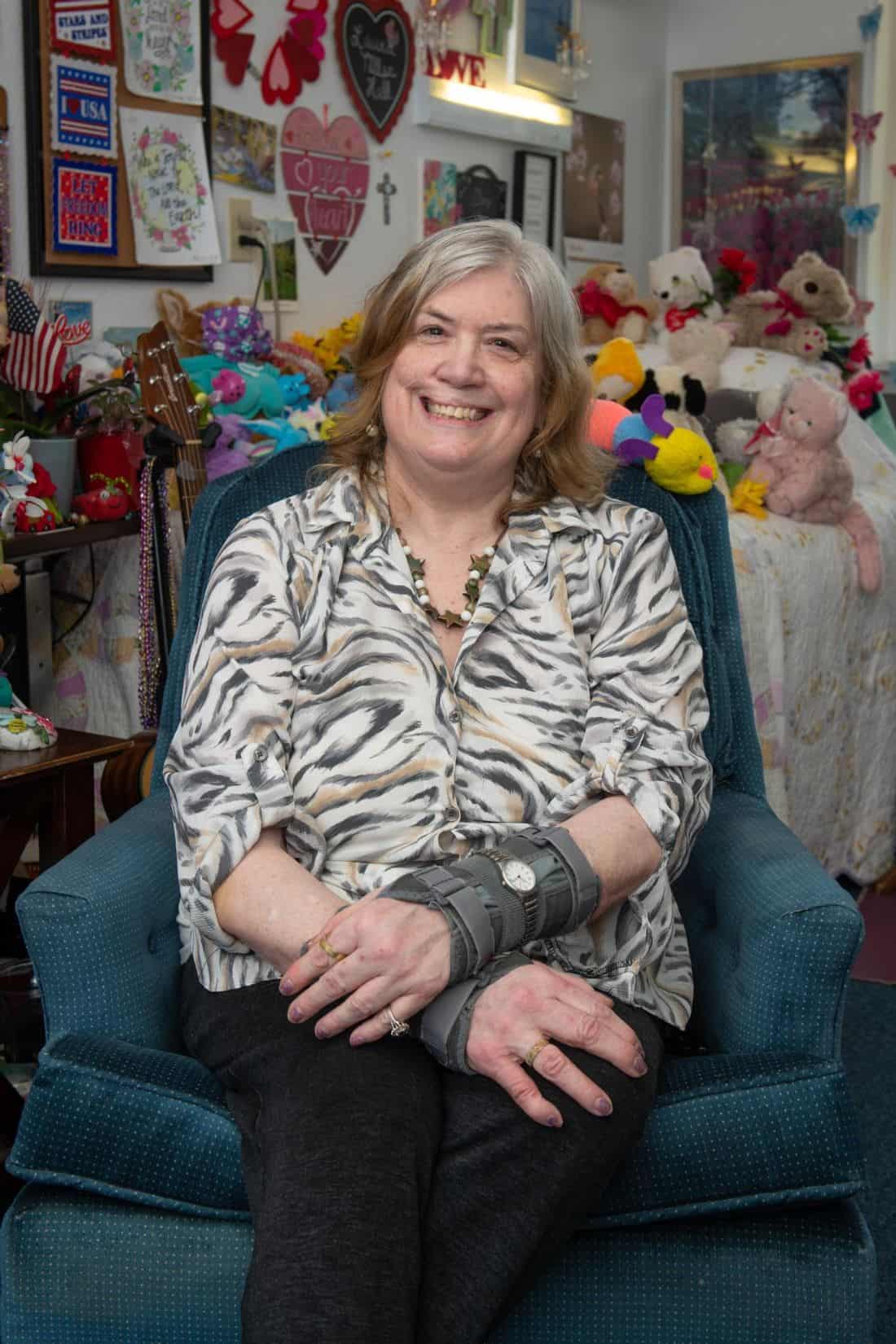 Smiling woman seated in a vibrant interior filled with stuffed animals.
