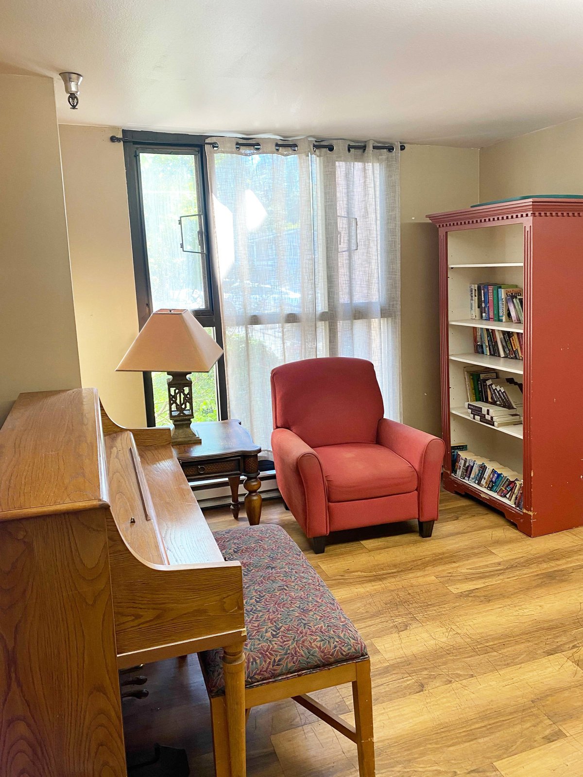 Cozy interior with a chair, piano, and bookshelf.