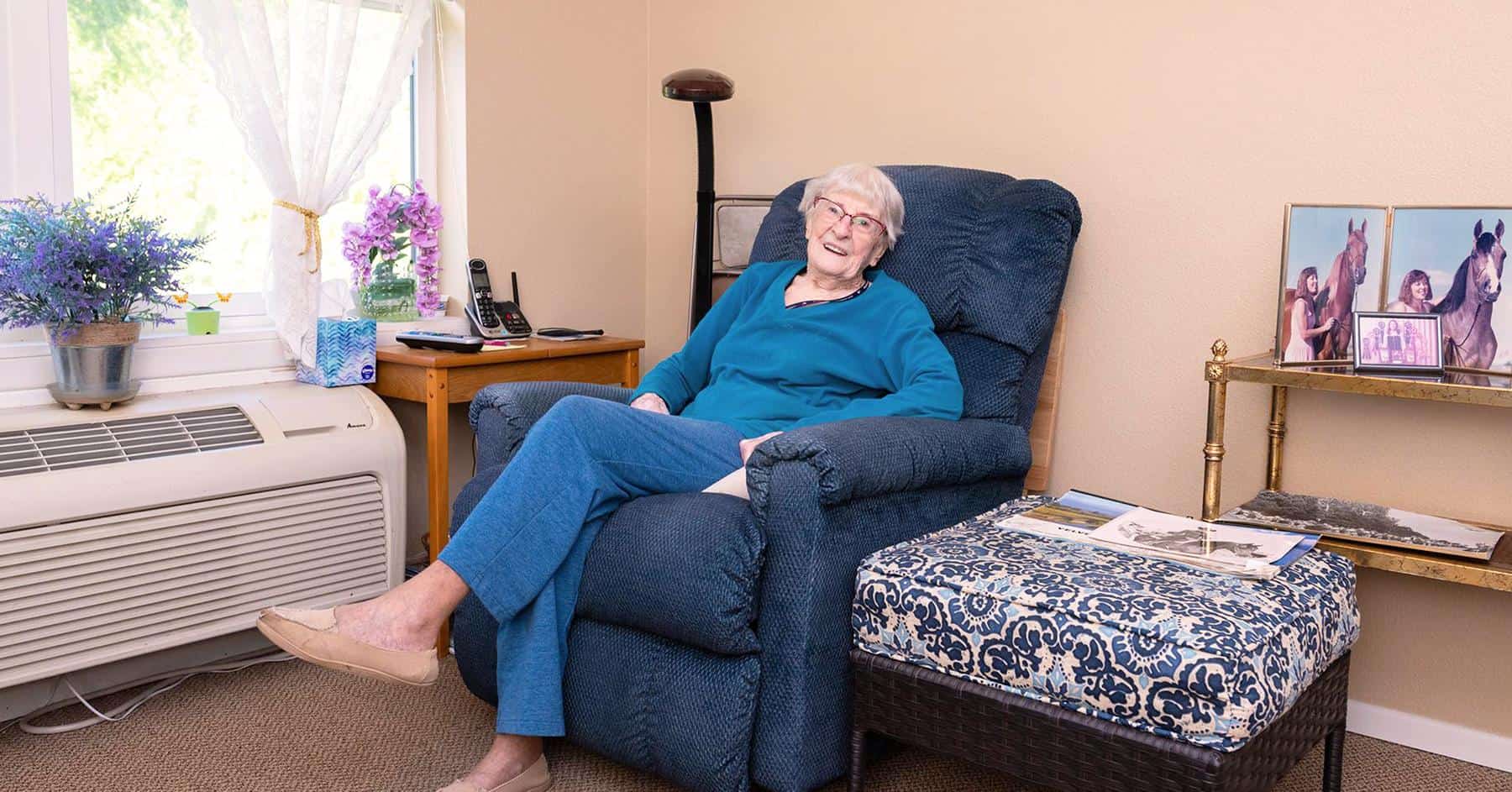 Resident relaxing in a cozy chair in a living space.