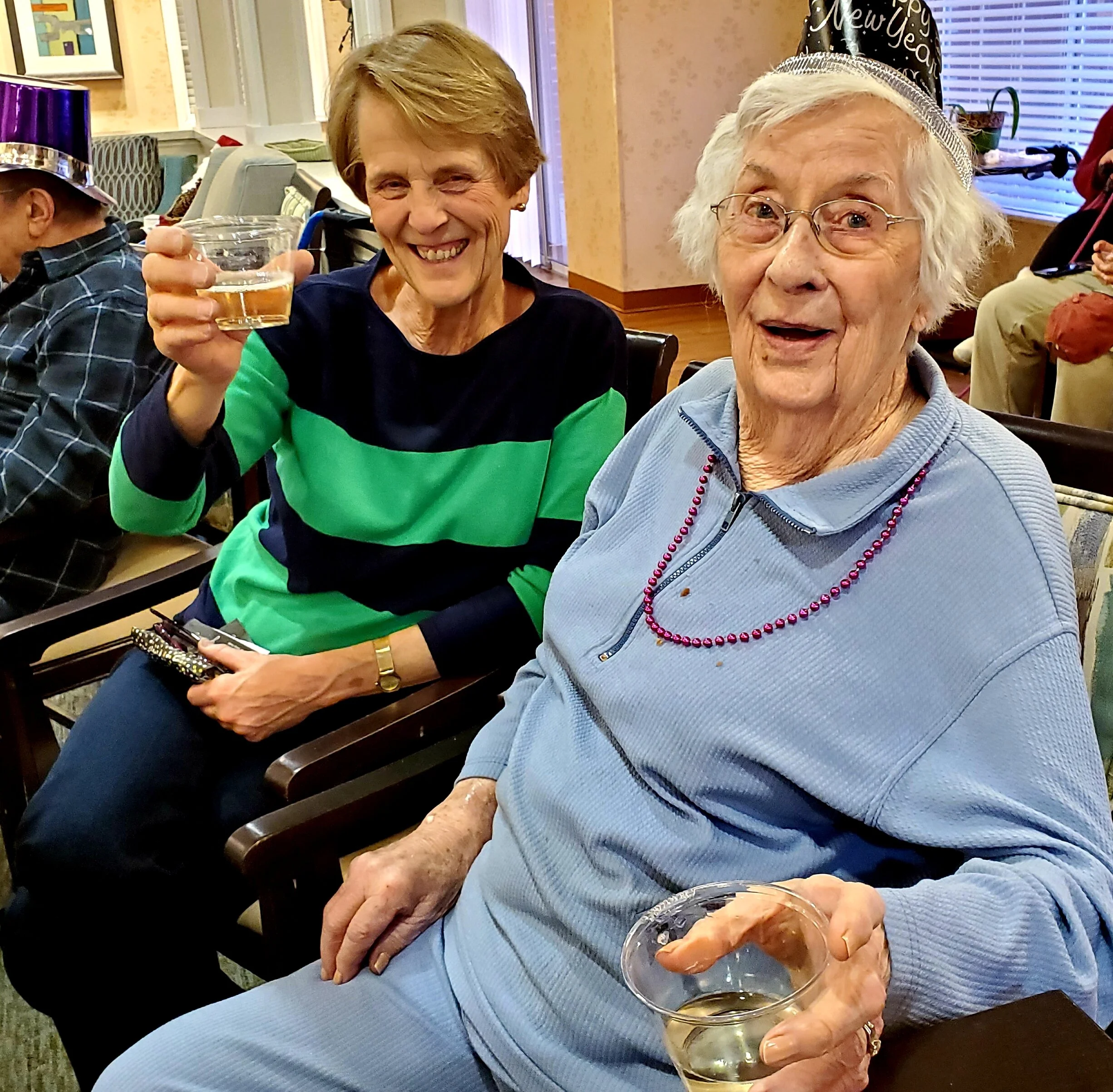 Two seniors enjoying a toast in a common area.