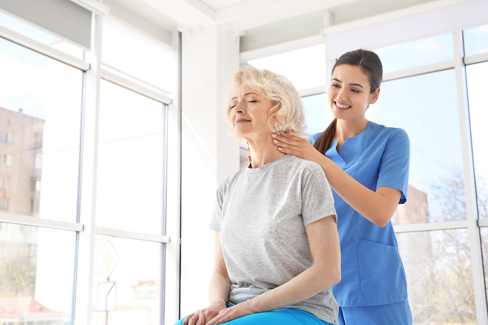 Caregiver assisting senior woman with a massage