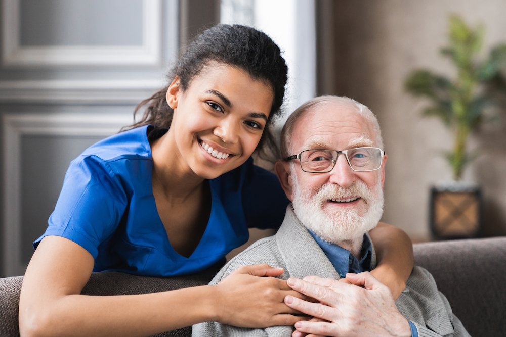 Caregiver and resident smiling together in a common area.