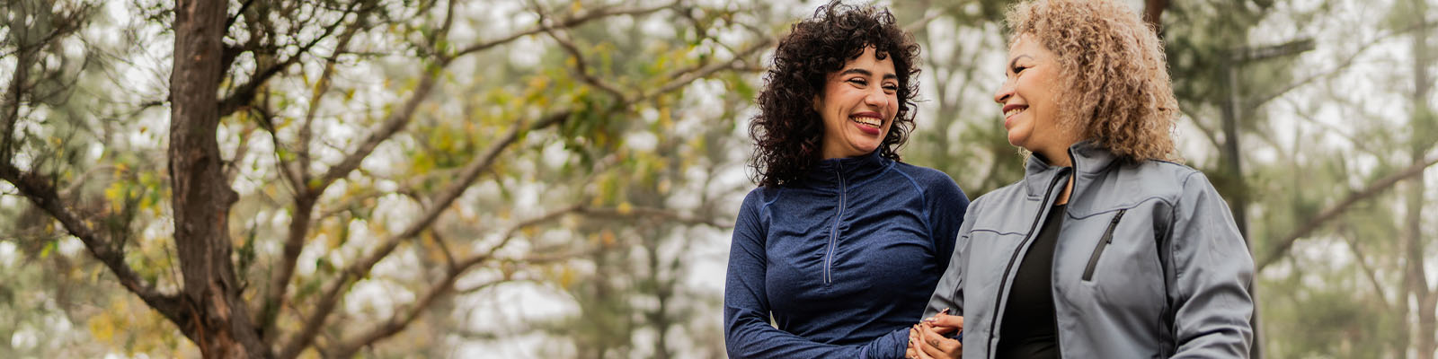 Two women smiling together in a garden.
