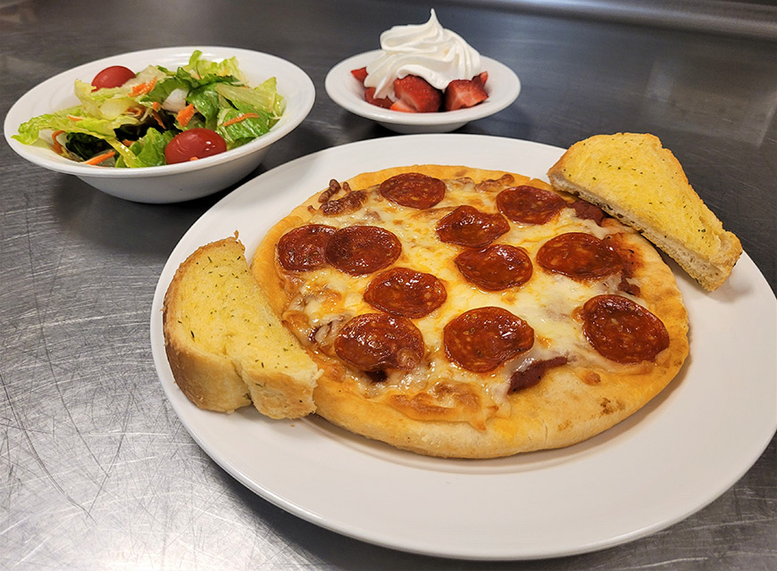 Plate with pepperoni pizza, salad, and dessert.