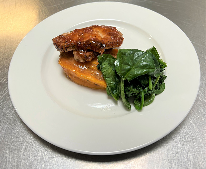 A plated meal with chicken and spinach on a white dish