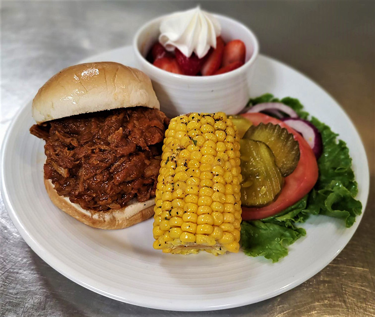 A plate of shredded barbecue chicken with sides