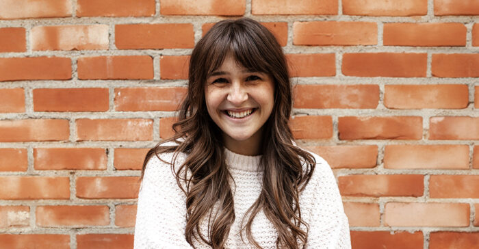 Woman smiling in front of a brick wall