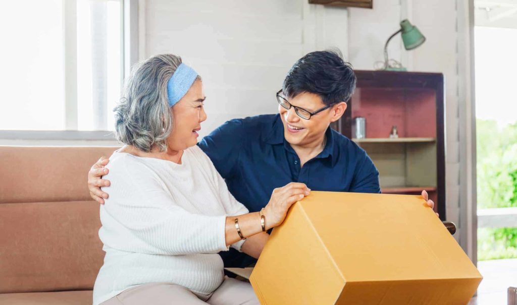 A resident engaging with staff while opening a box