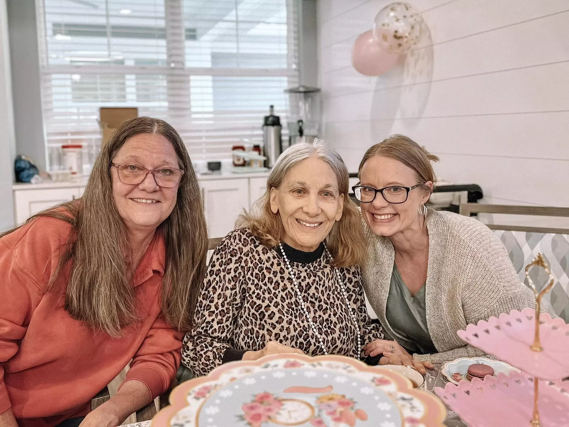 Three women smiling together in a cozy indoor setting